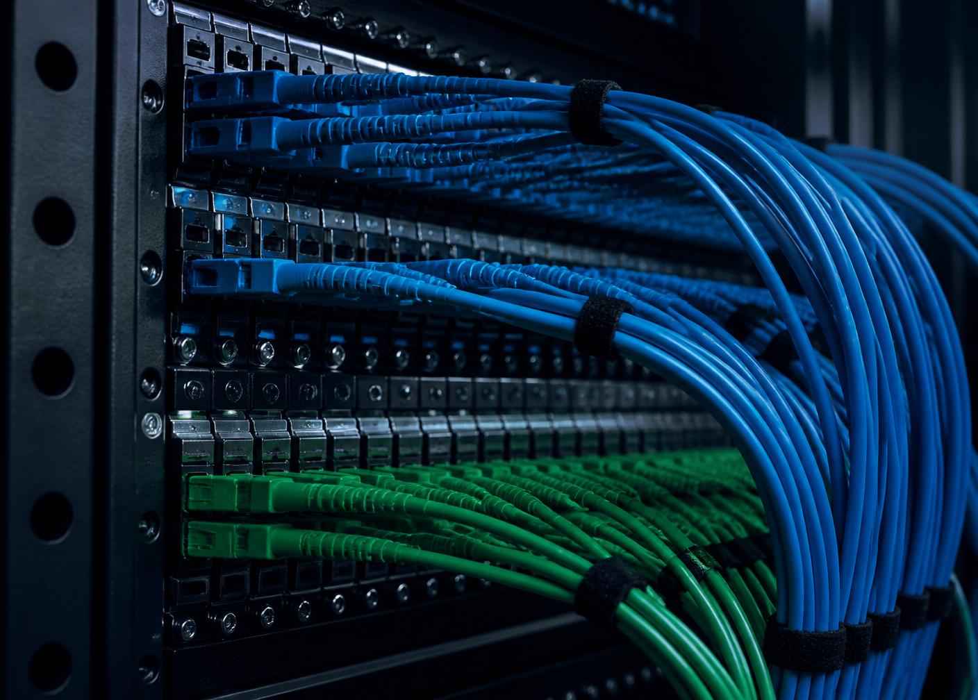 Structured fibre optic patch panel with blue and green cabling in a network rack